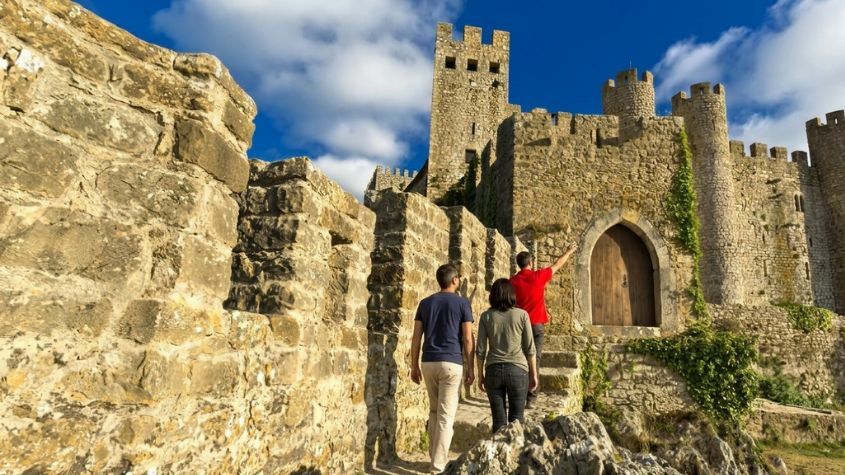 Couple of tourists walking along the walls of Óbidos Castle with a Living Tours guide