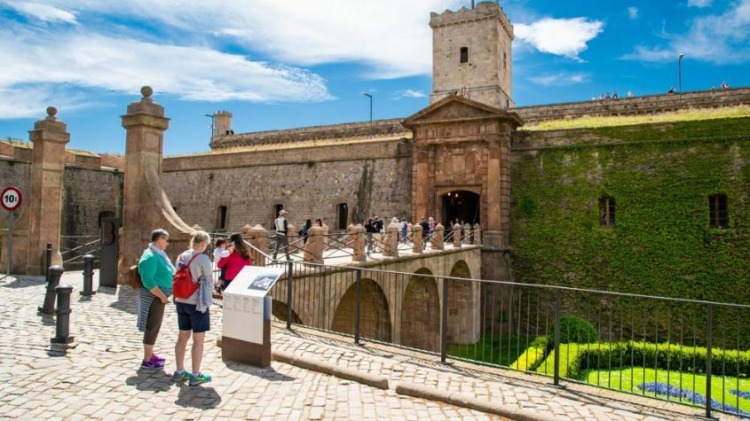 Casal de turistas à frente de monumento em Montjuic